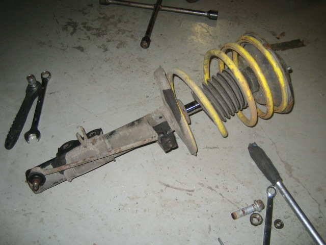 Hele fjærbeinet med demper og fjær og lenkearm er ute. Anbefaler å bruke fjærklemme!