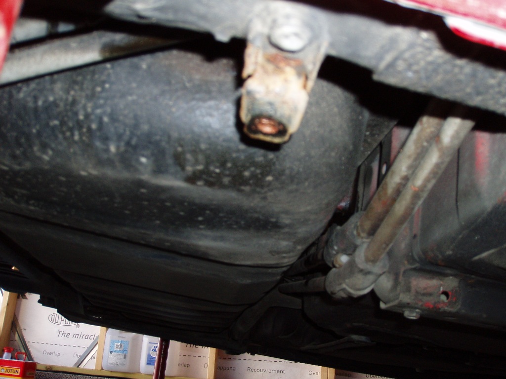 bensintanken sett fra siden med noe kjølestystemgreier i veien for en av skruene som må løsnes